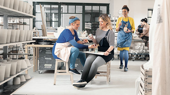 Kvinder sidder og laver keramik. De har kompressionsstrømper på.