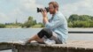 Ein Fotograf sitzt auf einem Steg. Er trägt eine Juzo Kniebandage