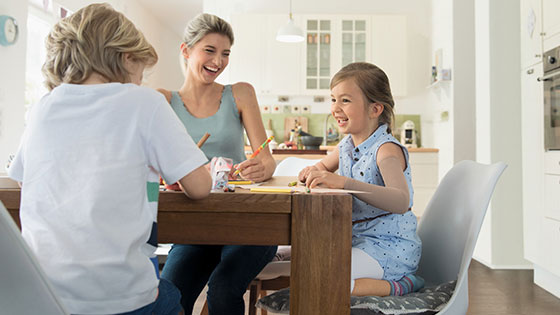 Arbehandling En familie sidder ved spisebordet. Den unge datter har et arret kompressionstøj på armen.