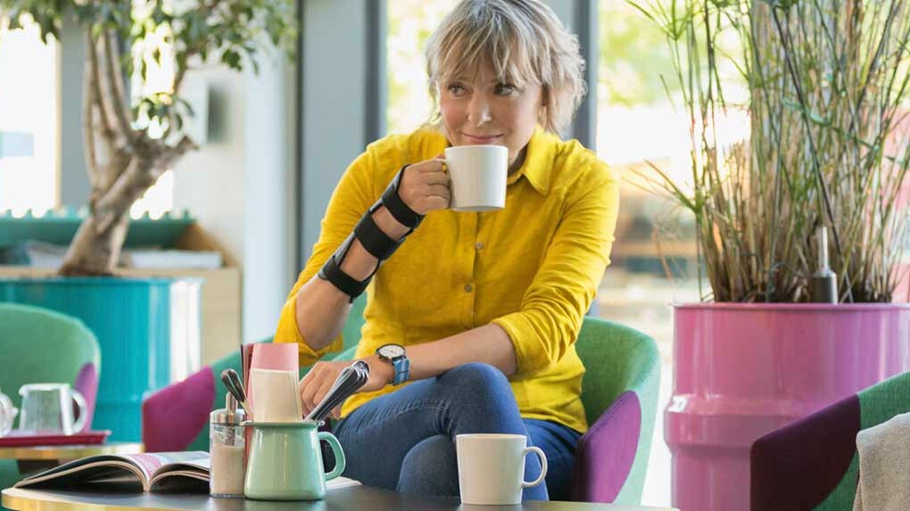 Karpaltunnelsyndrom Infoseite Frau trägt JuzoPro Manu Xtec Handgelenkorthese und hält eine Tasse in der Hand