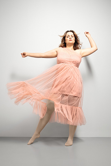 1. Lifestyle afbeelding Juzo Inspiration Vrouw met Juzo Inspiration en panty in amandel en roze jurkje