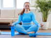 Frau in blauen Sportsachen meditiert auf einer blauem Matte sitzend