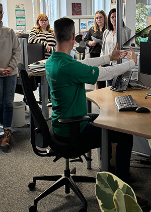 Ergonomie-Berater bei uns im Haus Ein Ergonomie-Berater sitzt an einem Schreibtisch und zeigt die richtige Einstellung des Arbeitsplatzes