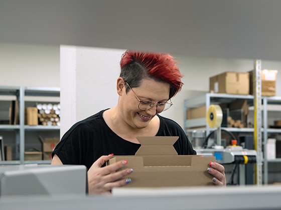Mitarbeiterin im Logistikzentrum Mitarbeiterin im Logistikzentrum faltet einen Karton