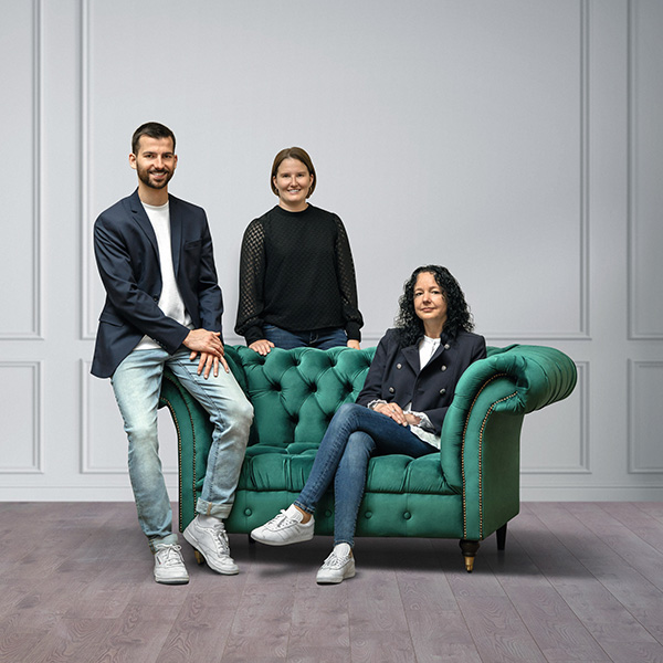 Die Abteilungsleitung der Juzo Akademie Auf dem Bild sieht man 2 Frauen und einen Mann, welche sich um ein grünes Sofa positioniert haben