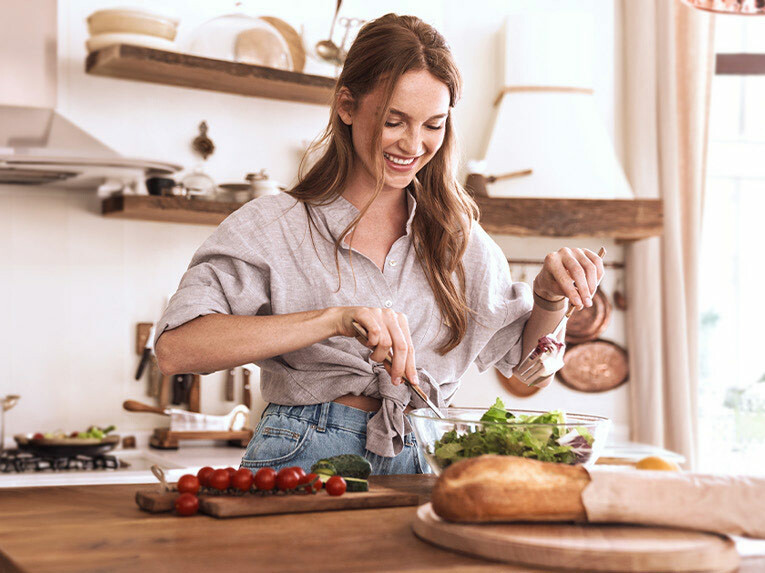 Eine lächelnde Frau bereitet sich gerade einen leckeren Salat zu