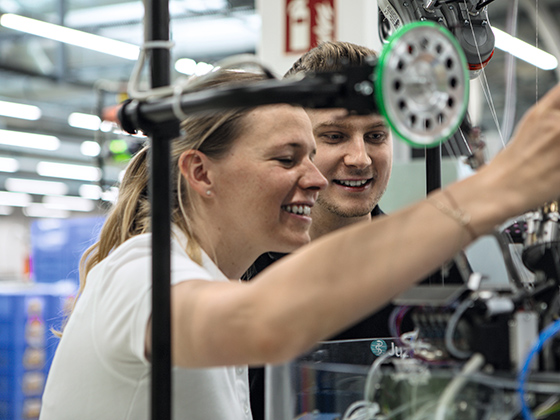 Gemeinsam ist man stärker Eine Frau und ein Mann betrachten eine Strickmaschine
