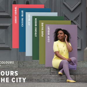 Eine Frau sitzt auf Steinstufen vor einem Tor. Sie trägt einen hellgelben Zweiteiler zu einer lilanen Kompressionsversorgung. Hinter ihr sieht man Farbfelder in den Trend Colours