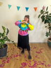 Eine Frau trägt ein buntes Hippie Outfit mit braunen Kompressionsstrümpfen.